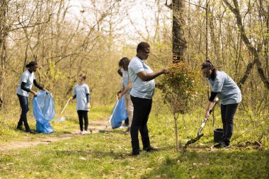 Çeşitli kadınlar orman habitatında birlikte küçük bir ağaç dikiyorlar, vahşi yaşama ve doğa ekimine katkıda bulunuyorlar. İnsanlar orman bitkilerini büyüterek gönüllü iş yapıyorlar..