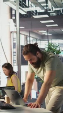 Ofisteki dikey video yönetimi dizüstü bilgisayardaki bulut hesaplama kaynaklarını kullanarak büyük ölçekli makine öğrenme modelleri yetiştiriyor. Şirket sistemlerini izleyen adam ayakta dururken dizüstü bilgisayarını kullanıyor