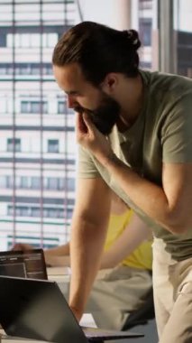 Ofisteki dikey video yönetimi dizüstü bilgisayardaki bulut hesaplama kaynaklarını kullanarak büyük ölçekli makine öğrenme modelleri yetiştiriyor. Şirket sistemlerini izleyen adam ayakta dururken dizüstü bilgisayarını kullanıyor