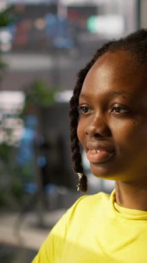 Dikey video yorgun Afrikalı Amerikalı programcı ofiste fazla çalışmaktan görme zorluğu çekiyor. İş yerindeki bir kadının gözlerini ovalamak için gözlük çıkarması, bilgisayar ekranına çok uzun süre bakması.