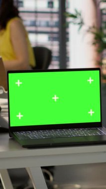 Çalışma alanındaki çalışma masasında, arka planda yazılım kalitesi güvencesi veren yöneticilerle birlikte dikey video ekranı var. Ofisteki Chroma anahtar defteri, iş yerindeki kadınla birlikte cihaz ve kamera üzerindeki kodlamayı denetliyor.