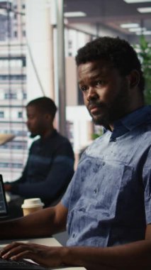 Dikey Videocu bilgisayar ekranındaki detayları kontrol ediyor, görevleri çözüyor. Afrika kökenli Amerikalı muhasebeci belgelerin kalite güvencesi beklentilerine uygun olduğundan emin oluyor.
