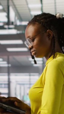 Dikey bilgisayar bilimcisi çalışıyor, defter kullanarak yazılım hata ayıklaması yapıyor, sorun giderme hataları yapıyor. Kadın ofiste duruyor, dizüstü bilgisayarla kodlama sorunlarını çözüyor, görevleri çözüyor, kamera A