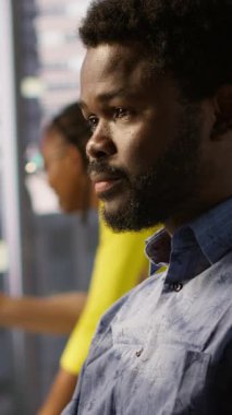 İşteki dikey video sistemi yöneticisi verileri işleyebilen ve analiz edebilen makine öğrenme modelleri yaratıyor. Ofisteki Afro-Amerikan bilişim uzmanlarını PC, kamera A kullanarak kapatın.