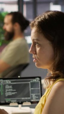 İşteki dikey video sistemi yöneticisi PC kullanarak AI yazılımının hata ayıklamasını yapıyor, kod satırlarındaki arızaları kontrol ediyor. BT uzmanı yapay zeka kodlama sorunlarını çözmek için