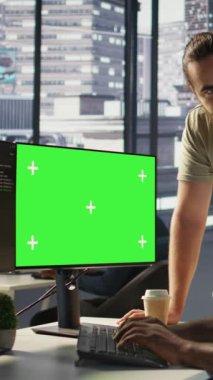 Yeşil ekranda yazılım hata ayıklaması yapan dikey video yöneticisi, iş arkadaşından yardım istiyor, kod hatalarını kontrol ediyor. İşçi, meslektaşı tarafından desteklenen, model bilgisayardaki kodlama hatalarını düzelten