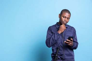 Üniformalı devriye memuru cep telefonundaki mesajlara cevap veriyor, koruma görevi sırasında arkadaşlarıyla iletişim kurmak için sosyal medya uygulamalarını kullanıyor. Güvenlik görevlisi internet sayfalarını kontrol ediyor.