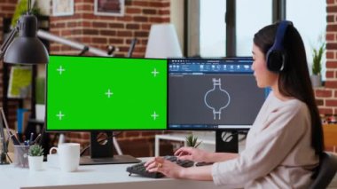 Endüstriyel mühendis CAD yazılımıyla çalışıyor ve evdeki modern bir çalışma alanında izole edilmiş bir model. Kurulum, endüstriyel tasarımın teknik tarafını vurgulayan çift monitörleri içeriyor. Kamera B.