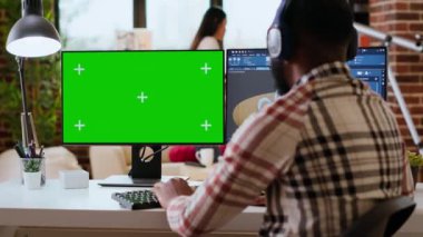 Erkek serbest tasarımcı yeşil ekran ve CAD yazılımı kullanarak 3D prototipler üzerinde çalışıyor. Ev işleri endüstriyel tasarımda verimlilik ve konfor arasındaki dengeyi vurguluyor. Kamera B.