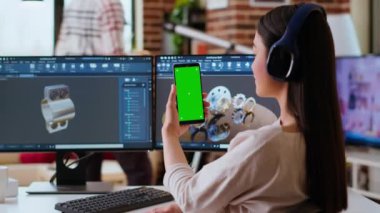 Asyalı bağımsız geliştirici kulaklıklar ve krom ekran ile çalışıyor, imalat endüstrisi için yeni bir prototip yaratıyor. Kadın 3D model mühendisi ev ofisinde. Kamera B.