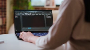 Asyalı kadın programcı ev ofis kurulumunda kodlama yazılımı üzerinde çalışıyor, dizüstü bilgisayarda daktilo ediyor. Bilişim uzmanı çoklu görev, yazılım geliştirme ve uygulama geliştirme için dijital araçlar kullanır. Kamera B.
