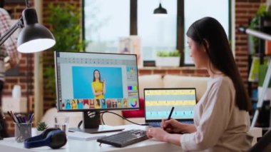 Asyalı grafik tasarımcısı iyi düzenlenmiş bir ev çalışma alanında fotoğraf rötuşlaması için düzenleme yazılımı kullanır. Kadın serbest yazar, yaratıcı bir sanat kariyeri için gerekli dijital aletleri kullanır. Kamera B.