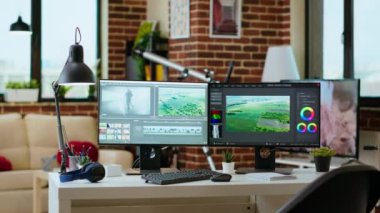 Oturma odasındaki modern dijital çalışma alanı teknoloji ve verimliliğe odaklandı, video oluşturma için post prodüksiyon araçlarını gösteren çift monitörler. Temiz masa kurulumu verimli video üretimini destekliyor.
