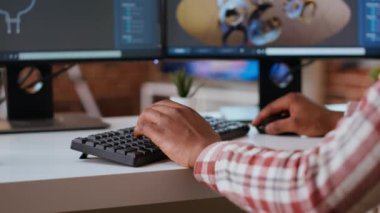 Erkek mühendis CAD yazılımı kullanarak modern endüstriyel arayüzde 3D prototipler tasarlıyor. Uzman, 3 boyutlu modelleme ve teknik uzmanlık yoluyla dişli ve makine araçları üretiyor. Kamera B.