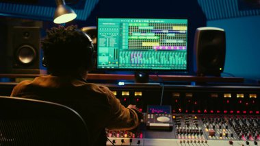 Ses tasarımcısı ses seviyesini karıştırıcı kontrol masasında ayarlıyor, profesyonel müzik stüdyosu konsepti. Yapımcı sesi açar ve miksaj konsoluna efekt ekler ekler, canlı şarkılar kaydeder. Kamera B.