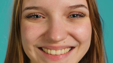 Neşeli, gülümseyen, eğlenen, arka planda izole bir kızın aşırı yakın çekimi. Işıl ışıl gülümseyen, pozitif yüz ifadesi ve iyi ruh hali olan rahat bir kadının portresi.