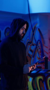 Dikey video Yalnız Kurt bilgisayar korsanı kurbanlardan bilgisayar virüsü kullanarak veri çaldıktan sonra çevrimiçi aktivitesini gizlemeye çalışıyor. Fark edilmemek için tablet kullanıyor.