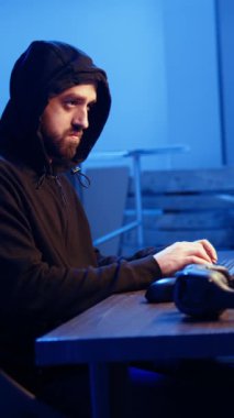 Dikey video Hacker yeraltındaki sığınak ve kodlamada saklanırken bilgisayar virüsü kullanarak kurbanlardan veri çalarken müzik dinliyor. Kulaklık takan düzenbaz programcı insanları takmaya ikna ediyor.