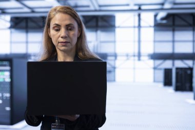 Veri merkezi programcısı laptop kullanarak veri tabanının güvenliğini ve güvenliğini sağlıyor. Sunucu çiftliğindeki kadın izinsiz erişimi ve iş için risk oluşturan şüpheli faaliyetleri engelliyor