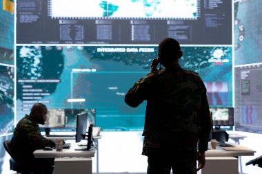 Ulusal güvenlik uzmanı, bir ordu kontrol odasında gerçek zamanlı uydu görüntülerini inceleyerek çok önemli bir istihbarat sağlıyor. Stratejik askeri operasyonları destekleyen izleme ekibi.
