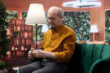 Yaşlı bir adam yanaklarına serum ve nemlendirici krem sürüyor. Yaşlanan deriyi korumak için her gün cildini şımartıyor. Bakım ve kişisel bakım için yenilenme losyonu kullanan kişi.