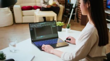 Asyalı kadın programcı ev ofis kurulumunda kodlama yazılımı üzerinde çalışıyor, dizüstü bilgisayarda daktilo ediyor. Bilişim uzmanı çoklu görev, yazılım geliştirme ve uygulama geliştirme için dijital araçlar kullanır. Kamera A.