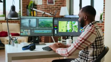 Erkek video üreticisi, zaman çizgisi düzenleme ve video üretimini yönetmek için profesyonel teknoloji araçları ve kurgu yazılımları kullanarak modern bir ofiste bir multimedya projesini düzenler. Evden çalışıyorum. Kamera A.