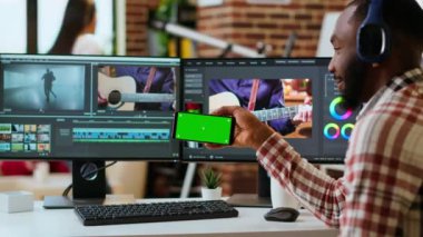 Afrikalı Amerikalı bir adam evinde, kurgu yazılımı ve çift ekran kullanarak uzay ekranının yanındaki bir müzik videosunu düzenliyor. Video üretimi ve serbest çalışma görevleri. Kamera B.