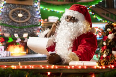 Noel Baba, Noel ruhunu yaymak için ateşin yanında mektuplar okuyor, telefonda sohbet ediyor. Geleneksel Noel sahnesi mevsimin sıcaklığını ve sihrini yakalar..