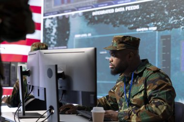 Yüksek teknoloji ofisindeki askeri personel dünya haritasındaki gözetleme faaliyetlerini ve uydu görüntülerini takip ediyor. Amerikan Ordusu personeli tehditlere karşı ulusal koruma sağlıyor.