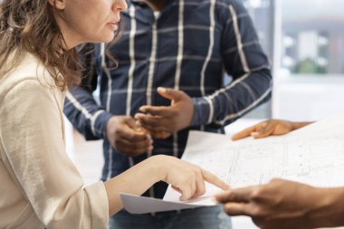 Emlakçı müşterilere ofis turunda mimari planlarda yardımcı oluyor, planları değerlendiriyor ve kiralama anlaşmalarını tartışıyor. Girişimciler şirketlerin yerini değiştirmeyi planlıyor. Kapat..