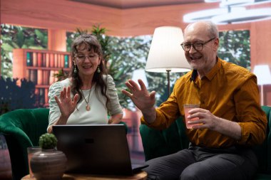 Uzaktan kumandalı video bağlantısı ile çocuklarla konuşan yaşlı bir çift torunlarını görmek için webcam kullanan bir laptop kullanıyor. İnternet 'te gevşemiş neşeli son sınıf öğrencileri sohbet ediyor..