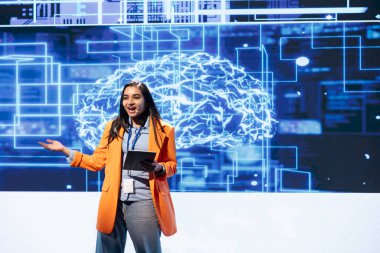 Sunum sırasında tablet kullanan iyimser programcı, gelişmekte olan yapay zeka teknolojilerinin yollarını keşfetmek işletmeleri geliştirebilir. Olaydaki neşeli kadın mikrofon ve cihaz kullanarak yapay zeka sunar.