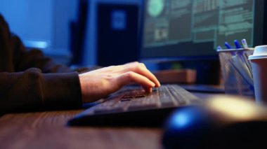 Gizli yeraltı sığınağındaki hackerlar klavyeye yazıyorlar, bilgisayarda kod satırları yazıyorlar, güvenlik sistemlerini virüsle geçmeye çalışıyorlar. Dolandırıcı, senaryo ve kamera üzerinde çalışıyor. Yakın çekim.