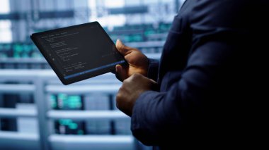Yüksek teknolojili bir tesiste, ağ sorunlarını yamamak için tablet kullanarak yavaş veri aktarımı yapan bir mühendis. Sunucuların performansını ve bağlantısını etkileyen işçi düzeltme hatalarını kapat, kamera A