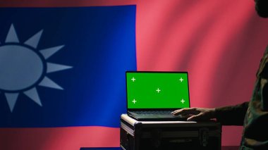 Taiwanese insurgent using military tech on green screen laptop to identify threats from enemies. Taiwan freedom fighter using software on mockup notebook to relay info to war front lines, camera B clipart