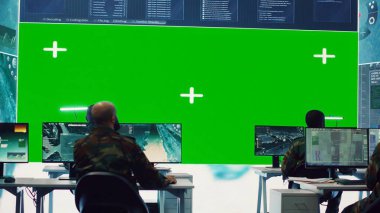 Geniş ekran izole bir ekranda faaliyet gösteren çeşitli er grupları yeşil ekrana bakar ve komuta merkezindeki askeri operasyonlara yardım etmek için istihbarat toplarlar. Askeri tesis üssü. Kamera A