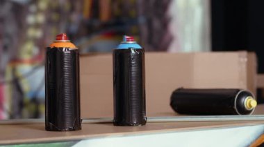 Endüstriyel depodaki sprey kutulara graffiti çizimleri koyun ve kimse gelmesin. Bulanık arka plandaki suçlular tarafından suç yuvası olarak kullanılan yer altındaki boya kutularına odaklan.