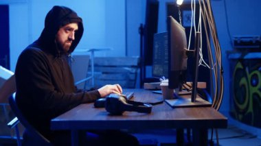 Hacker yeraltı sığınağında saklanırken müzik dinliyor ve PC virüsü kullanarak kurbanlardan veri çalıyor. Kulaklık takan kaçak programcı fidye virüsü yüklemek için insanları kandırıyor, kamera A