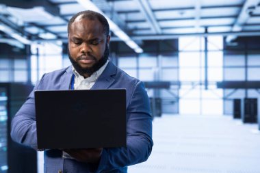 Sunucu odasında güvenlik önlemlerini uygulamak ve korumak için dizüstü bilgisayar kullanan bir mühendis. Sistemleri yetkisiz erişimden koruyor. Veri merkezi çalışanı dizüstü bilgisayar kullanarak donanım yüklemesi yapıyor