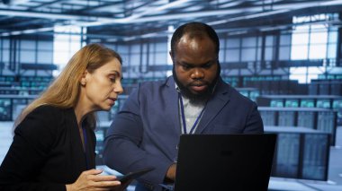 Cihazları kullanarak veri merkezini yöneten ekip çalışması teknisyenleri. Sunucu odasında bilgisayar ve tabletle veri merkezi altyapısını optimize eden iş arkadaşları, kamera A