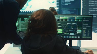 Hükümetin bilgisayar korsanları ekibi bilgisayar ve büyük ekranı kullanarak dijital güvenlik ve siber savunma önlemleri üzerinde çalışıyor. Uzmanlar siber operasyonlar, ağ güvenliği ve sunucu korumasına odaklanıyorlar. Kamera A.