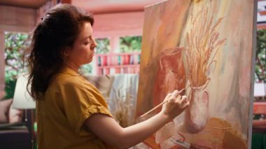 Ressam, sanat atölyesindeki modern boya fırçalarını kullanarak bir sanat eseri için doğal köy dekorasyonlarından ilham alıyor. Sanat sürecinde motivasyon ve yaratıcılıkla çalışmak. Kamera B.