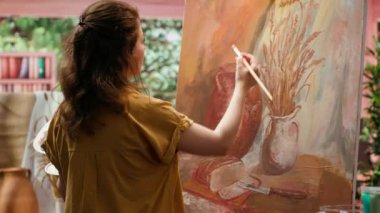 İlham verici ressam, atölyede bir başyapıt yaratmak için bir tuval üzerinde çalışır, kılları titizlikle boya uygulamak için kullanır. Yaratıcı süreçte eşsiz bir resim yapma becerisini gösteriyor. Kamera A.