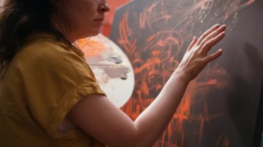 Bir sanat stüdyosunda, sanatçı bir parmak boyası başyapıtı yaratmak için suluboya boya boya boya kullanır. Yetenekli ressam, el izleriyle rengarenk bir sanat yaratma ilhamı gösteriyor. Kamera B.