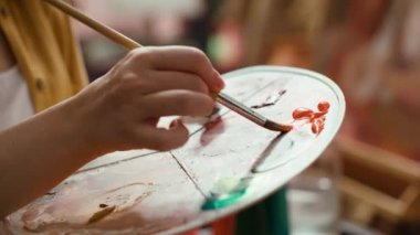 Bir sanat stüdyosunda, ressam bir paletin üzerine suluboya boya boyalar karıştırır ve tuvalde kırsal bir başyapıt yaratır. Aletlerle resim yapan ve yeteneğini, sanat eserlerini gösteren bir kadın. Kapatın. Kamera A.