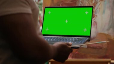 Stüdyoda yeşil ekran modeli olan Afrika kökenli Amerikalı sanatçı, belli bir tekniğe sahip yeni bir resim üzerinde çalışıyor. Ressam, eserleri için suluboya ve akrilik boya kullanıyor. Kamera A.