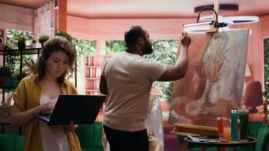 Ressamlardan oluşan bir ekip, sanat ve zanaat atölyesinde yeni bir kırsal şaheser üzerinde işbirliği yapıyor. Çırağı tuvale suluboya boya sürerken bir yandan da dizüstü bilgisayarda ilham arayan bir kadın. Kamera B.