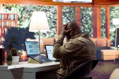 Stresli işadamı, ev ofisinden finans ve ekonomi konularıyla ilgileniyor ve teslim tarihlerini karşılamak için baskı altında çalışıyor. Şirket hesaplarını yönetmek, finansal planlama yatırımı.