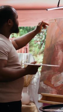 Dikey Video Sanatçısı, bir boya fırçasıyla bir tuvale suluboya resimler uygular ve çarpıcı bir sanat eseri yaratır. Ressam canlı renkler ve dinamik fırça darbeleri eğlence etkinliği olarak kullanır